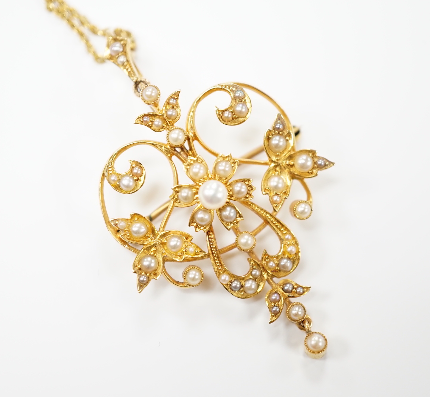 An Edwardian 15ct and seed pearl cluster set drop pendant brooch, 40mm on a later 375 chain.